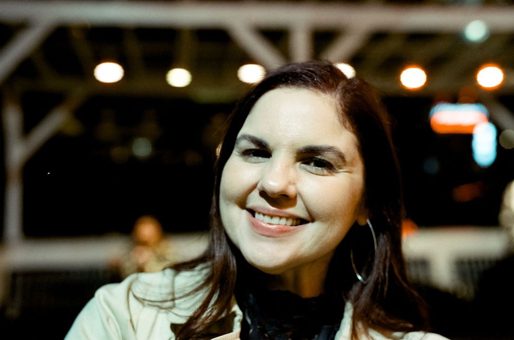 Person smiling warmly at night under ambient lighting.