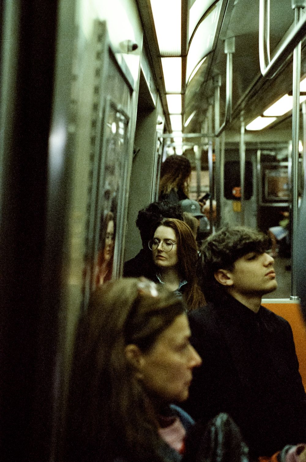 Commuters riding in a brightly lit subway car.