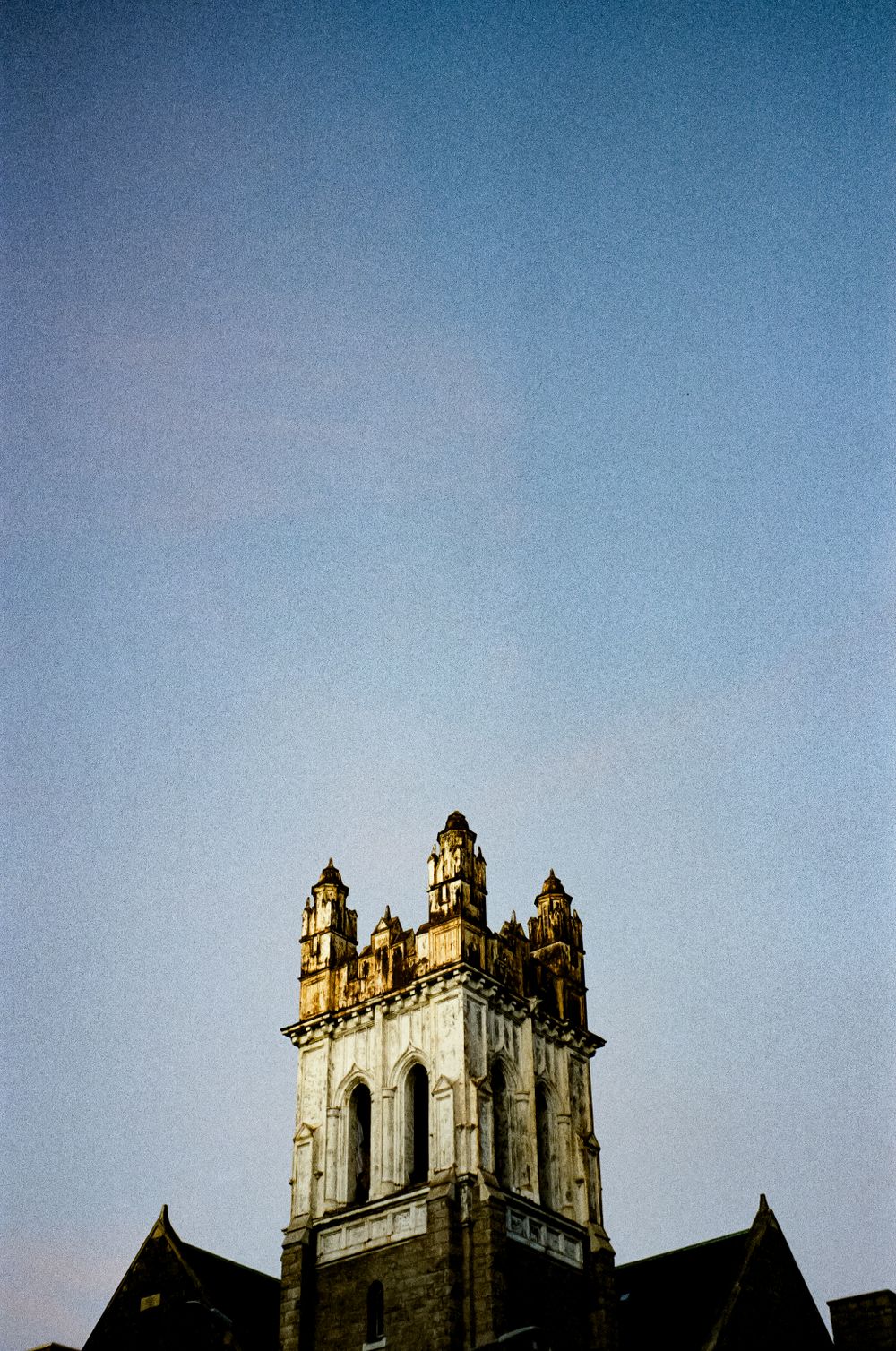 Gothic stone church tower with ornate spires rising against a clear blue sky.