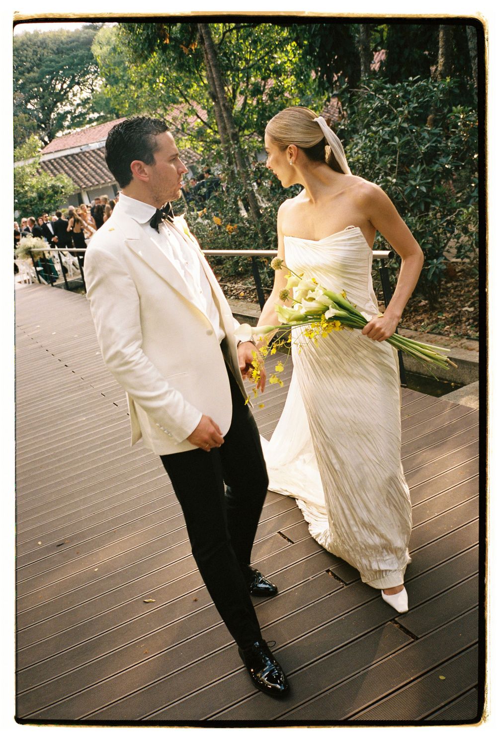 A couple sharing a playful moment on a wooden deck at their wedding celebration.