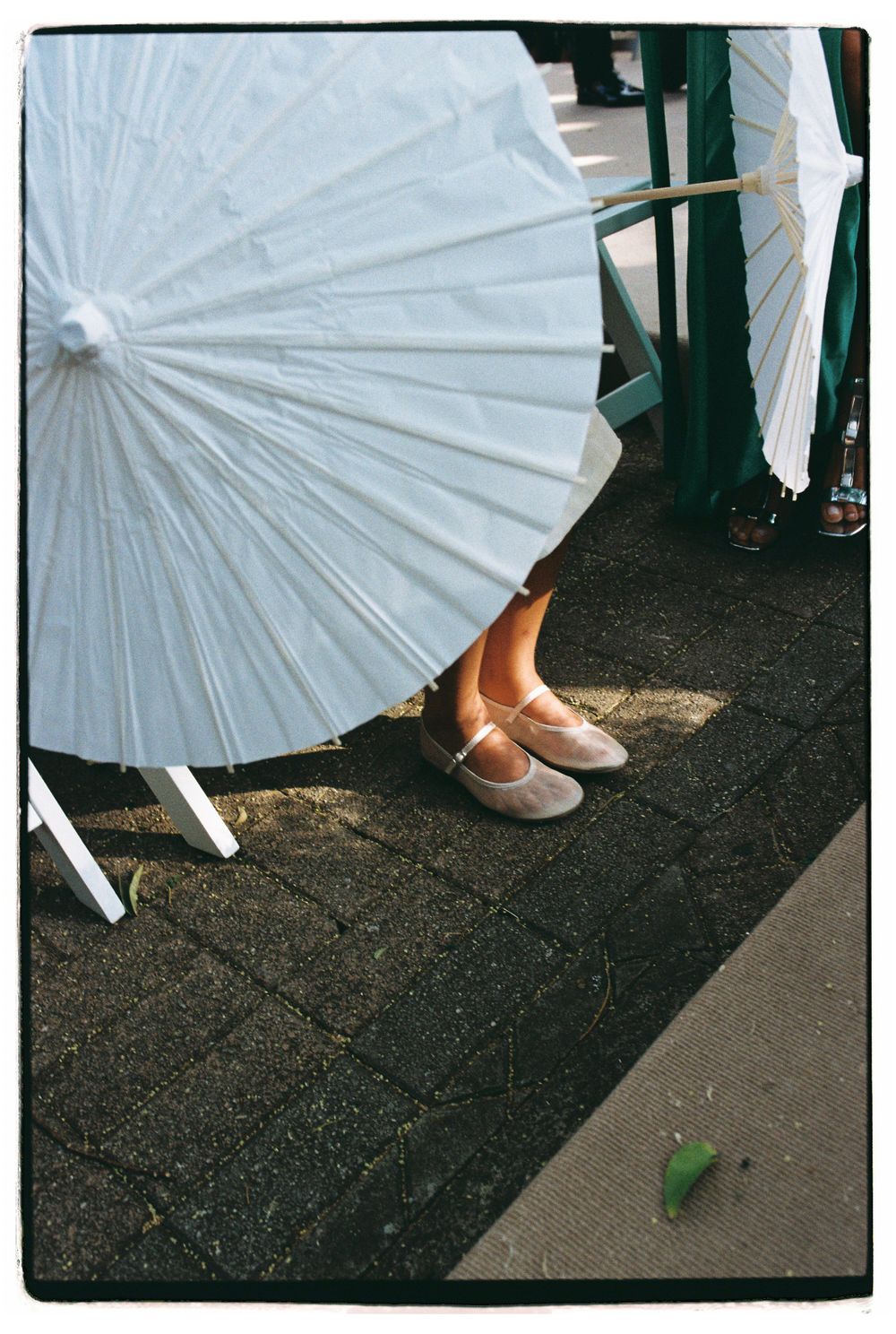 White paper parasol and casual shoes on a sidewalk on a sunny day.