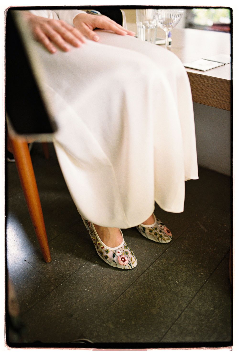 Close-up view of floral embroidered ballet flats paired with a flowing white dress.