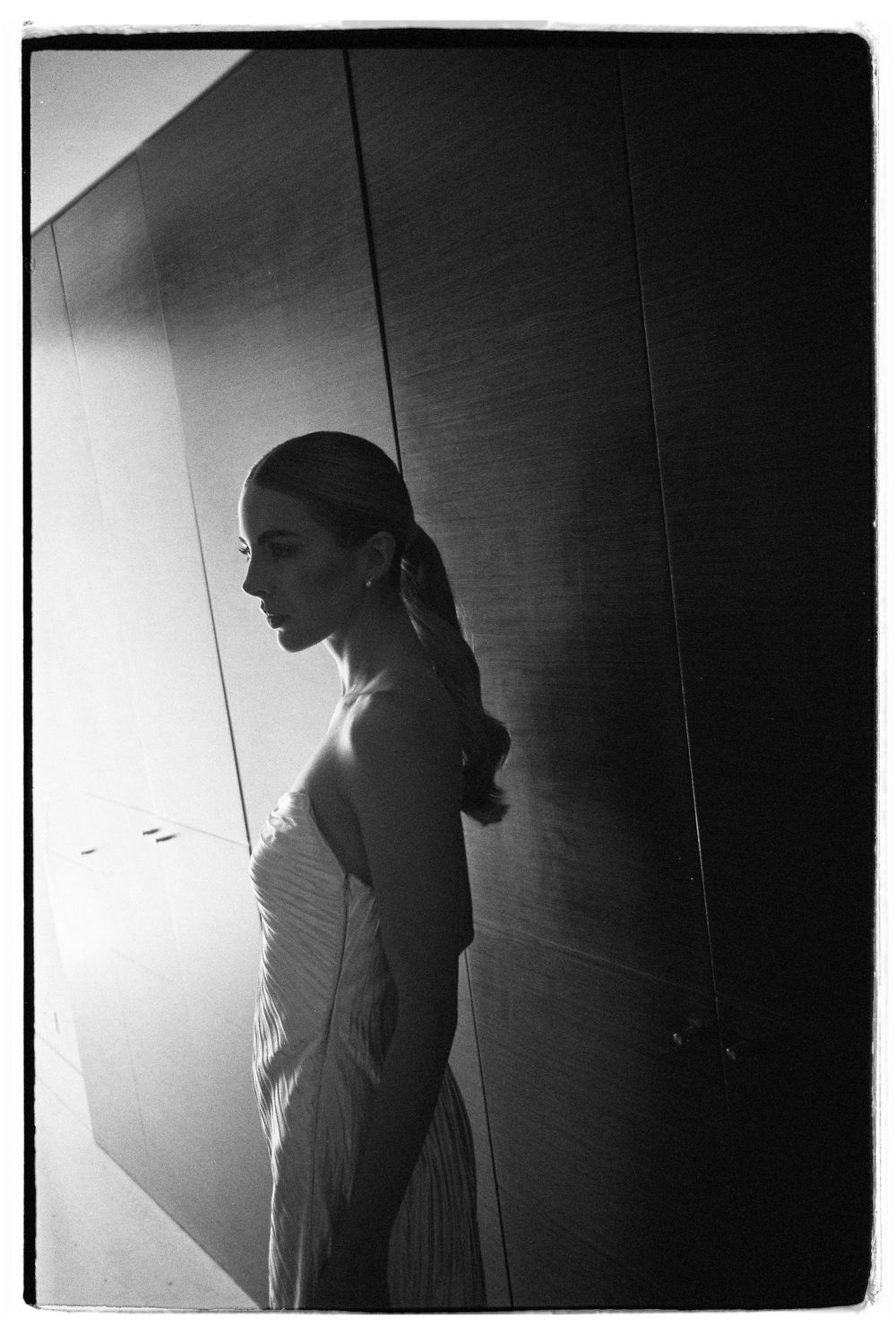 Dramatic black and white silhouette of figure in elegant dress against wall.