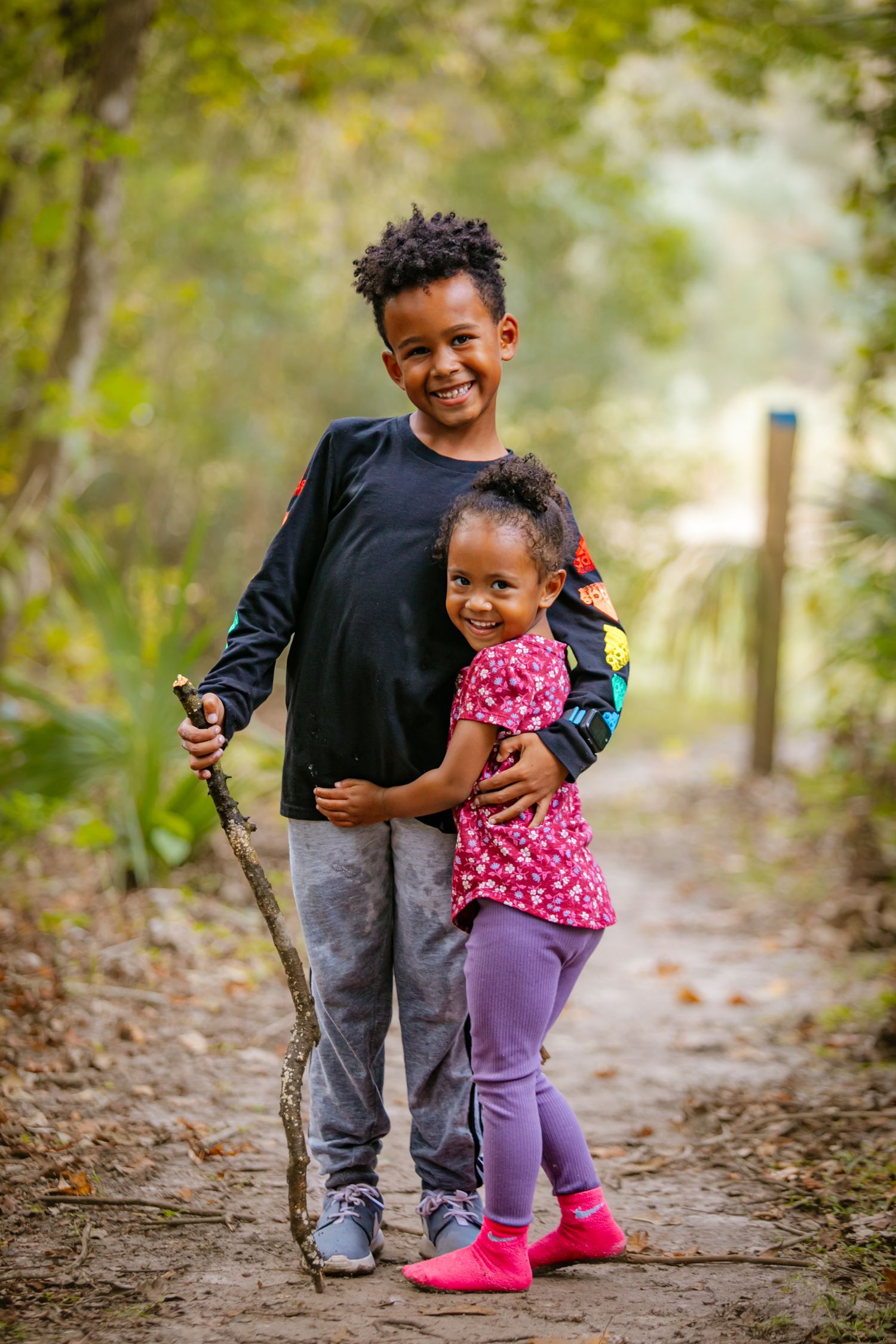 Two siblings share a happy moment together while exploring a wooded trail.