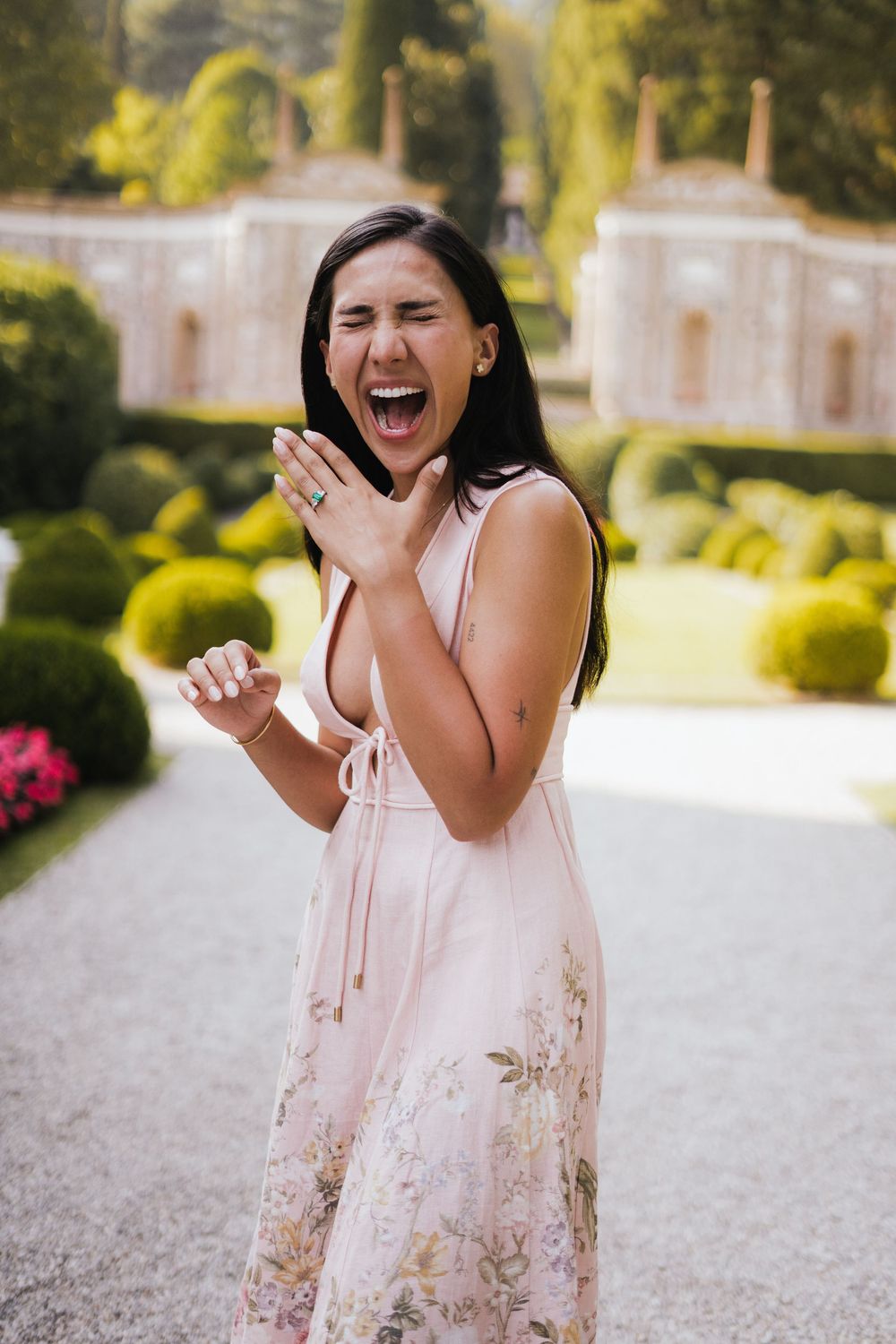 Joyful expressions and laughter in a sunlit garden with decorative landscapes and elegant structures.