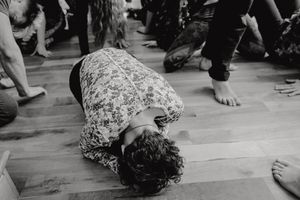 Dancer lies on wooden floor during expressive dance performance.