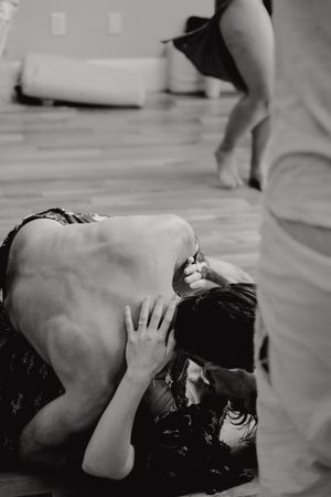 An intimate black and white photograph of dancers in close contact on a wooden floor.