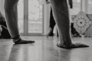 Close-up black and white photo of bare feet on a polished wooden floor.