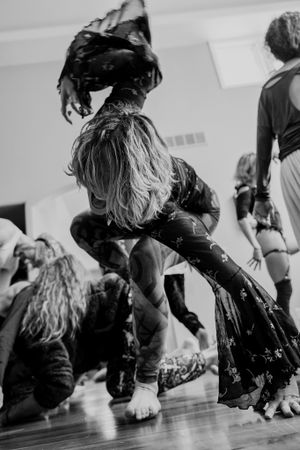 Dynamic black and white shot of dancer in flowing dress moving on wooden floor.