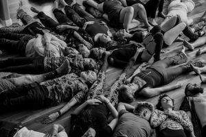 Large group lying on the floor together during what appears to be a workshop or group activity session.