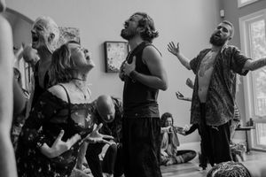 A group of people engaged in an animated discussion or performance in a casual indoor setting.
