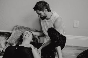 An intimate black and white scene of two people during a dance or movement exercise.