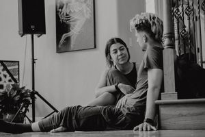 Black and white candid photo of two people sharing a lighthearted moment on stairs.