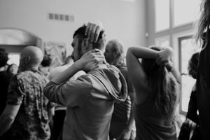 Group of dancers with arms raised during an indoor dance session.