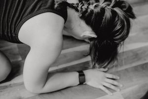Black and white photo of a person stretching or resting on wooden steps.