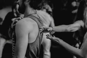 Close-up black and white photo of dancers' shoulders and arms during movement.