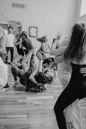 Dynamic black and white shot of people dancing and moving expressively in a studio space.