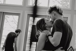 Intimate black and white photo of couple embracing and dancing near a window.