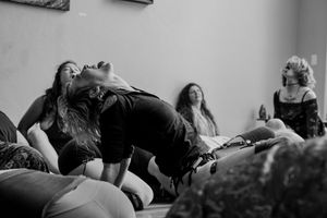 A dynamic black and white photo showing movement and dance on cushions during a workshop or class.