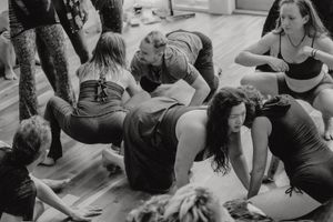 Black and white photo of dance students practicing floor movements in a group class.
