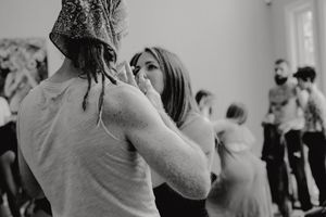 Black and white shot of people dancing and embracing in an intimate workshop setting.