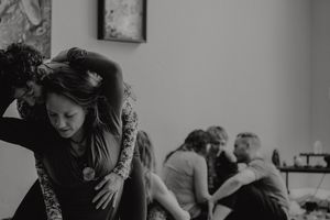 A moody black and white photo of people interacting in an indoor space.