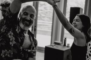 Two dancers share a joyful moment during a dance class in black and white photography.
