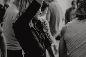 Black and white photo capturing raised arms and movement during a dance event.