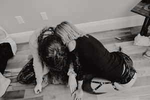 A black and white image showing someone bending forward on a wooden floor.