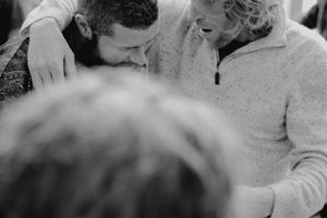An intimate black and white candid moment showing people in close conversation.
