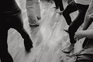 Low angle black and white shot of feet and legs dancing on a wooden floor.