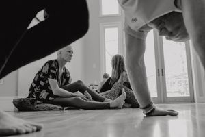 A high angle view of people sitting on a hardwood floor in a sunlit room.