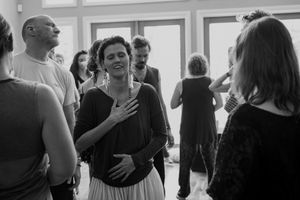 Black and white image of dancers engaged in an expressive workshop moment.