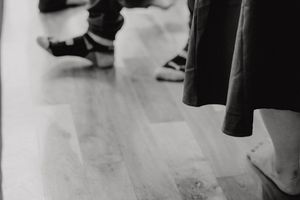 Black and white detail shot of shoes and clothing on a wooden dance floor.