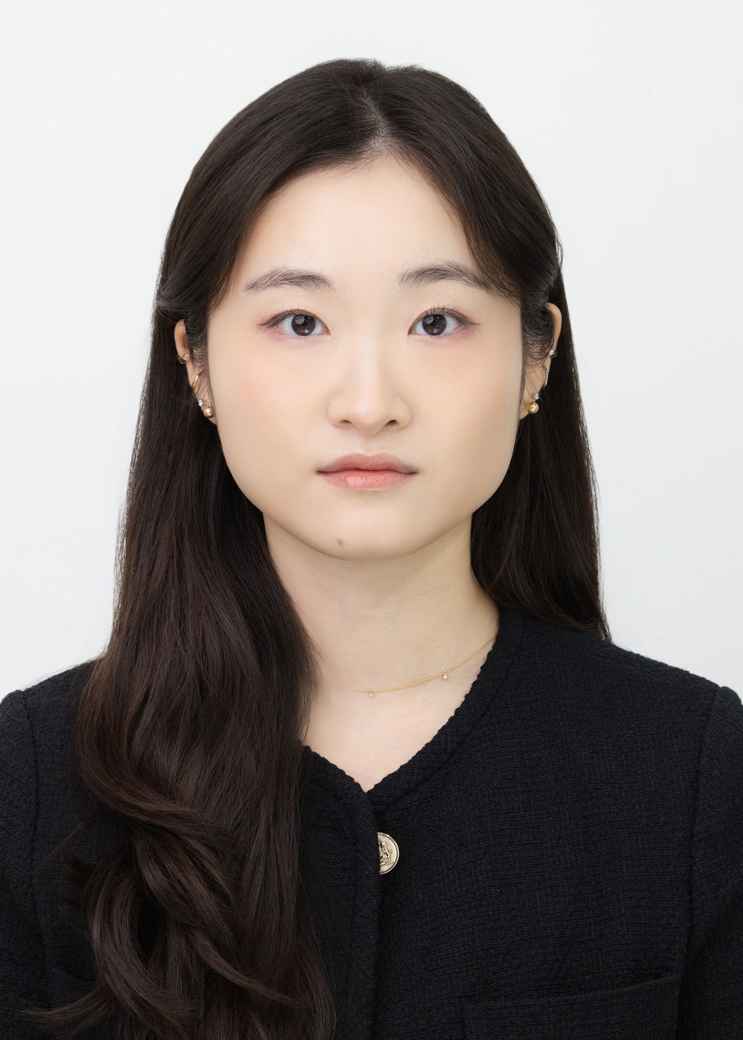Professional headshot portrait against a white background wearing a black blazer and crescent moon necklace.