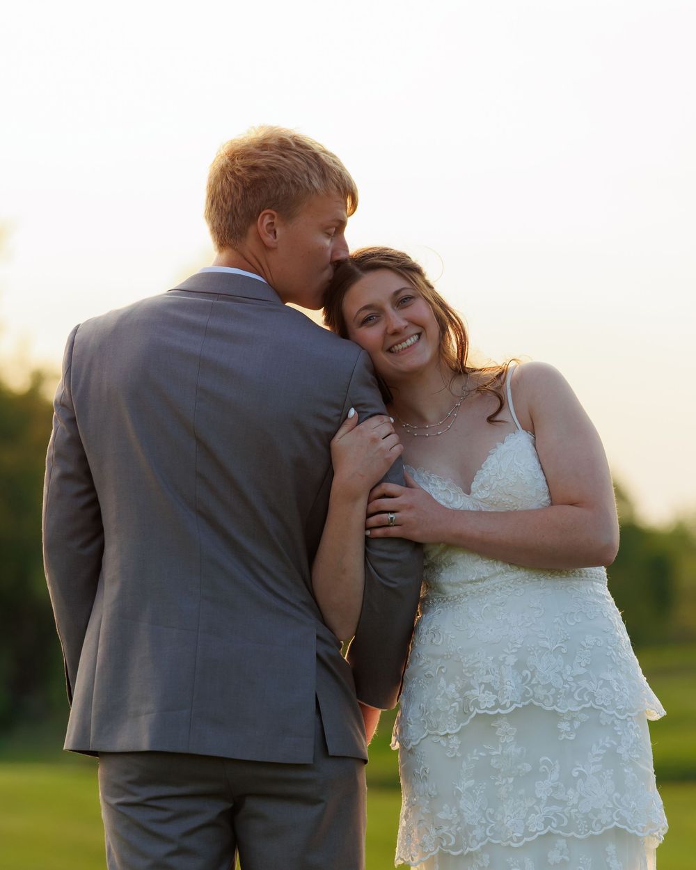 Happy wedding couple sharing an intimate moment and laughing together outdoors at sunset.