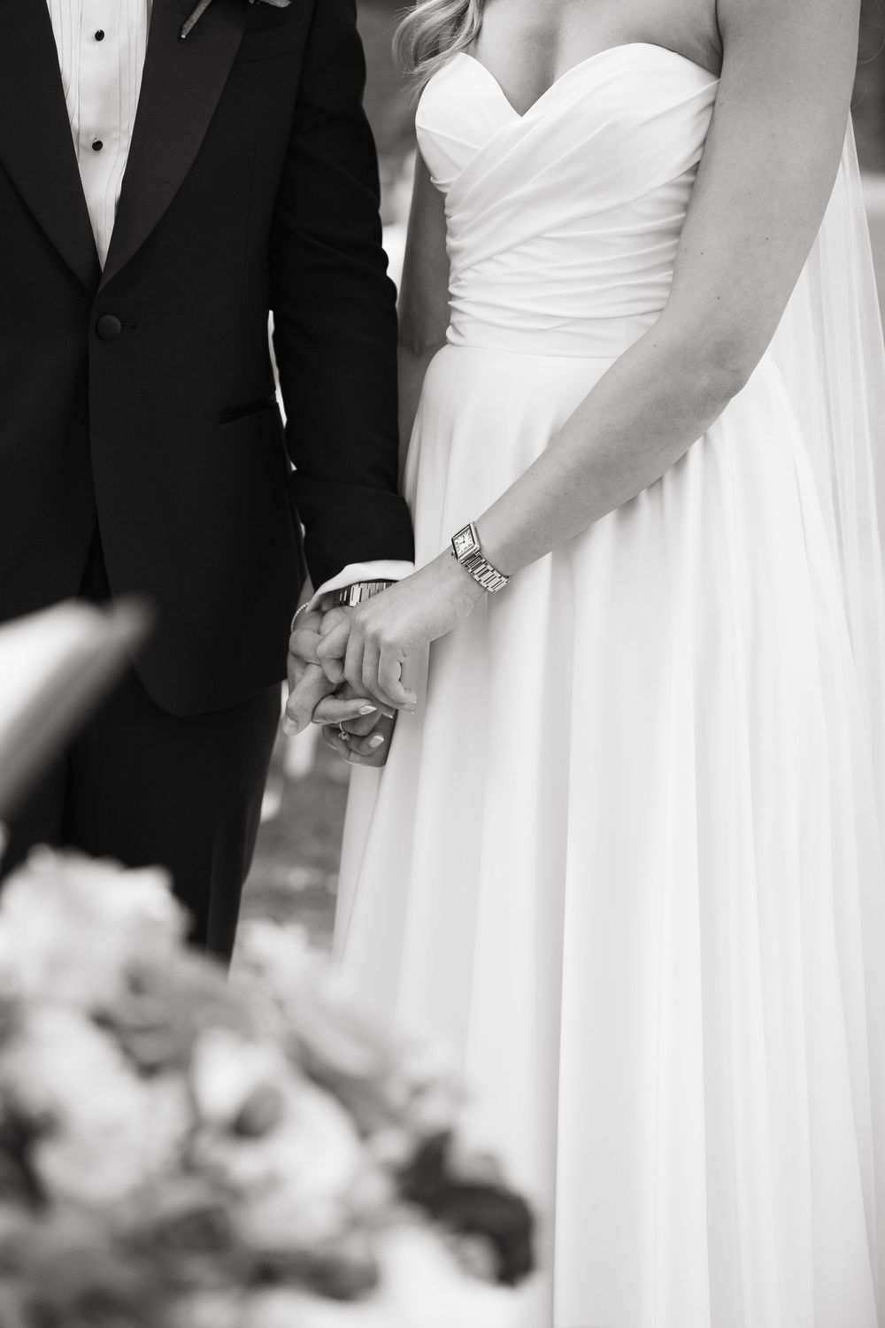 Black and white wedding party lineup showing bridesmaids in white dresses and groomsmen in tuxedos standing together.