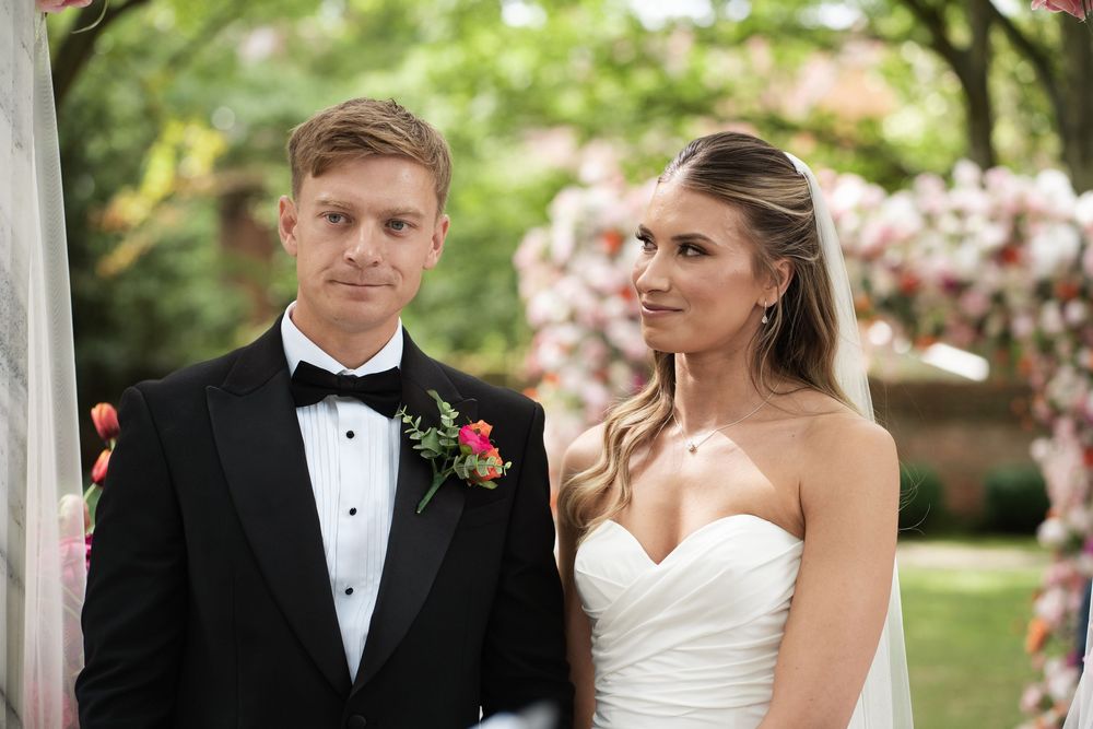A newlywed couple shares an intimate moment under a white gazebo on their wedding day.