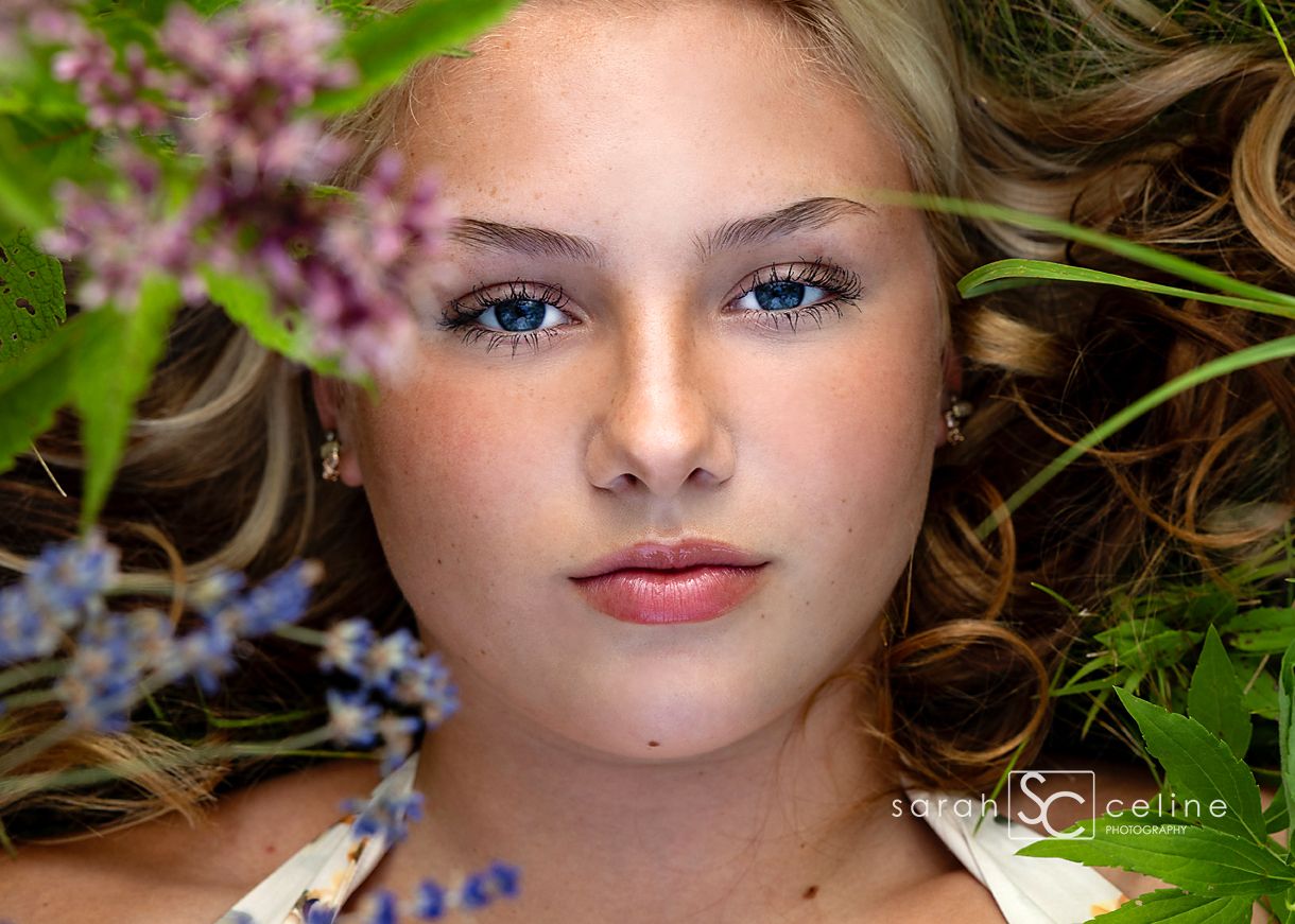 A close up portrait surrounded by delicate pink and purple flowers against a natural outdoor background.