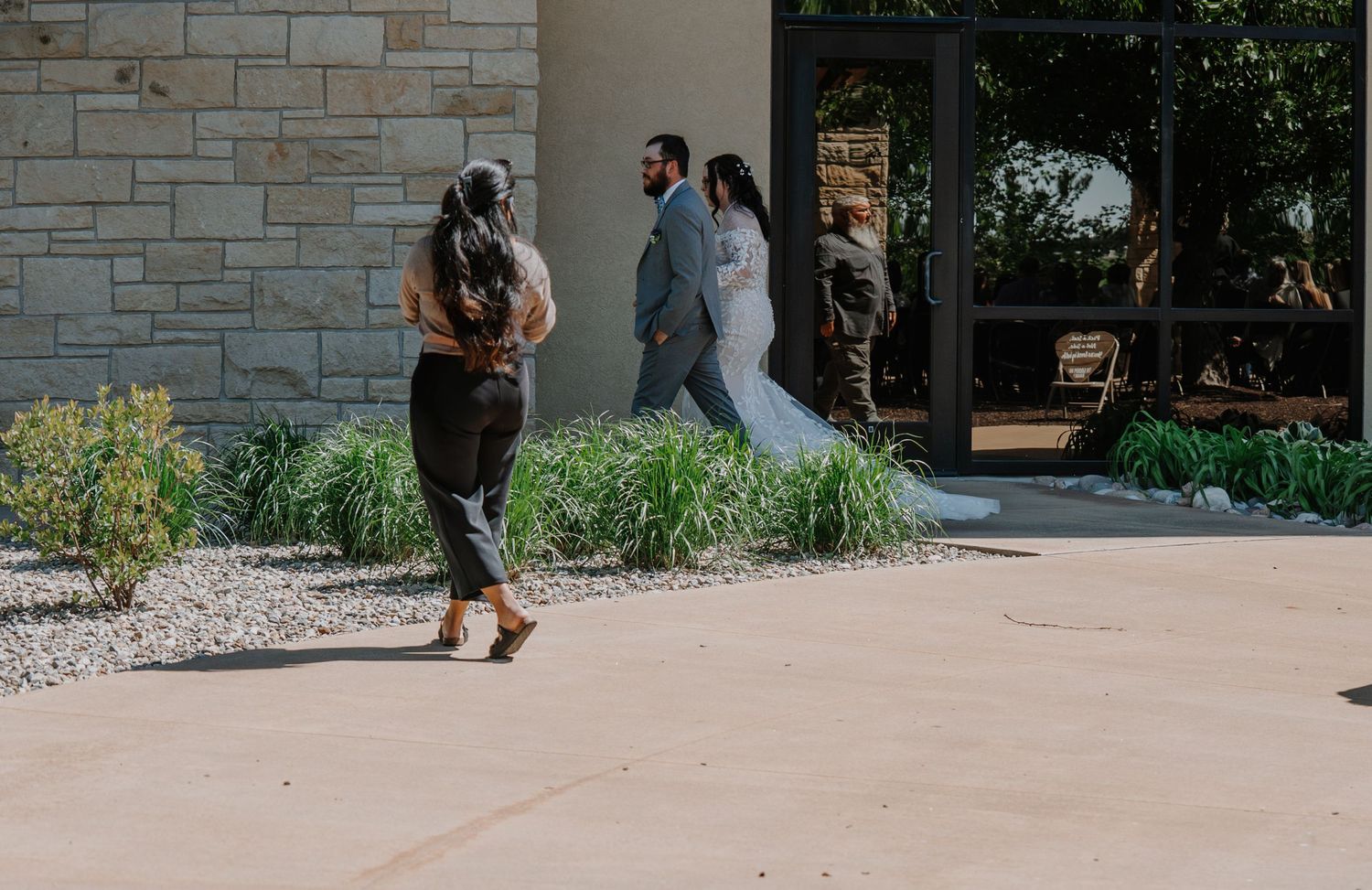 A wedding ceremony setup outdoors with stone walls, greenery, and dark wood chairs arranged in rows.