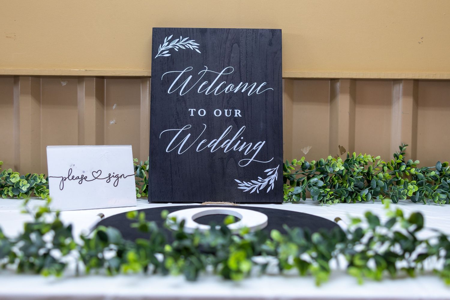 Wedding welcome signage displayed with greenery and decorative elements.