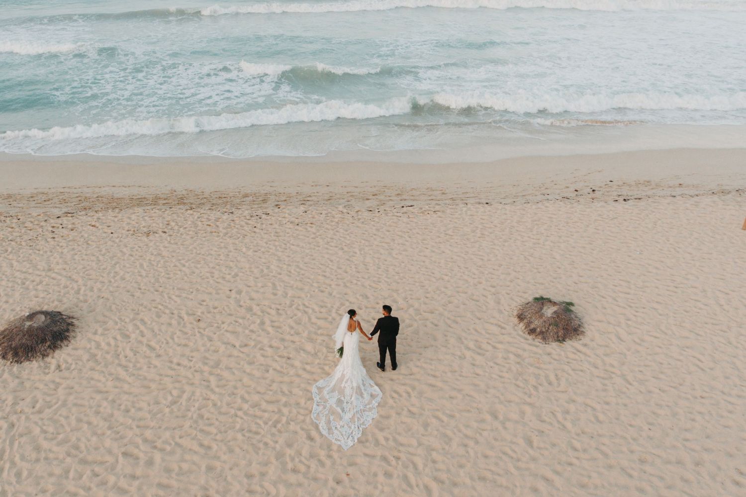 A beautiful beach wedding photo session with a long lace train gown against the ocean waves.