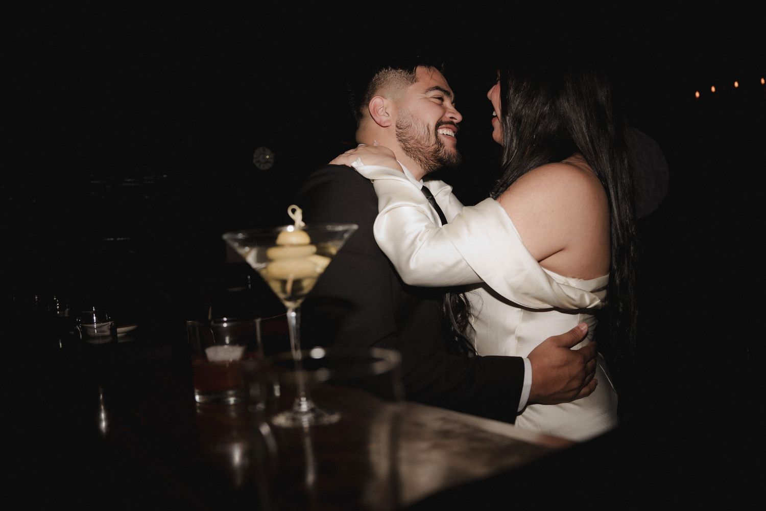 A romantic moment captured in a dimly lit bar with soft ambient lighting.