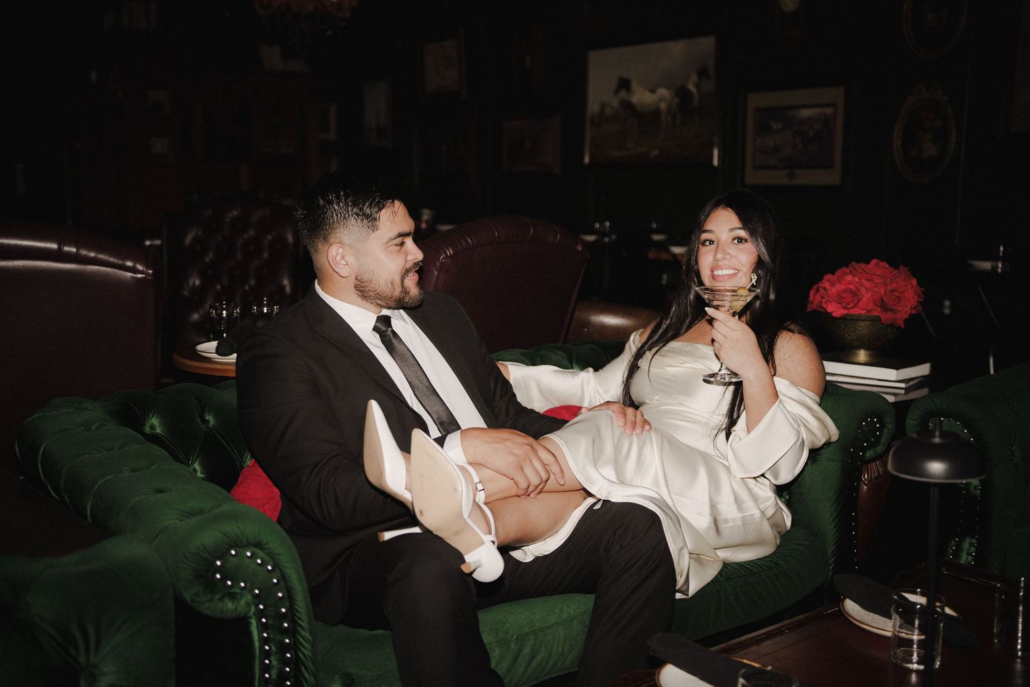 A couple shares an intimate moment in front of an ornate vintage mirror.