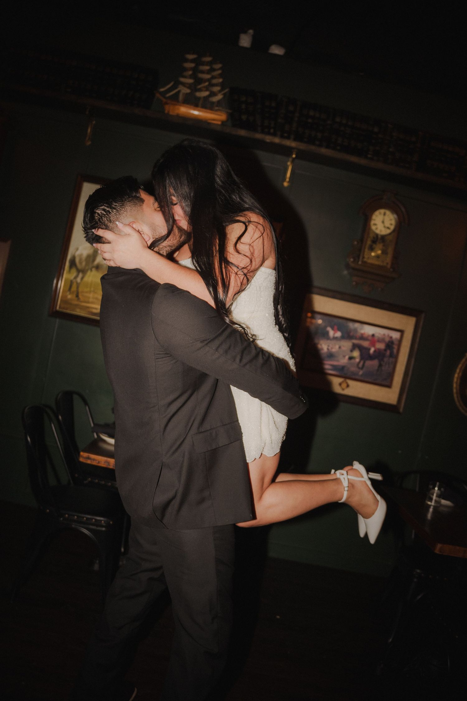 A romantic embrace captured in a dark, moody setting with dramatic lighting.