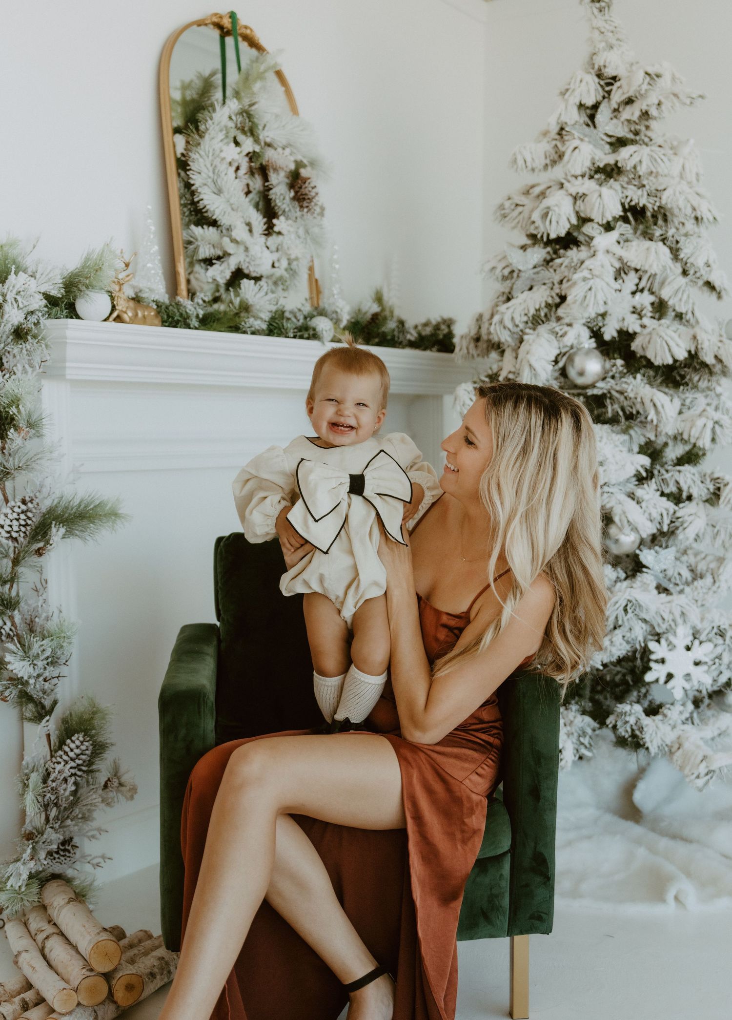 Sweet holiday portrait featuring a little one wearing white in front of a snowy flocked Christmas tree backdrop.