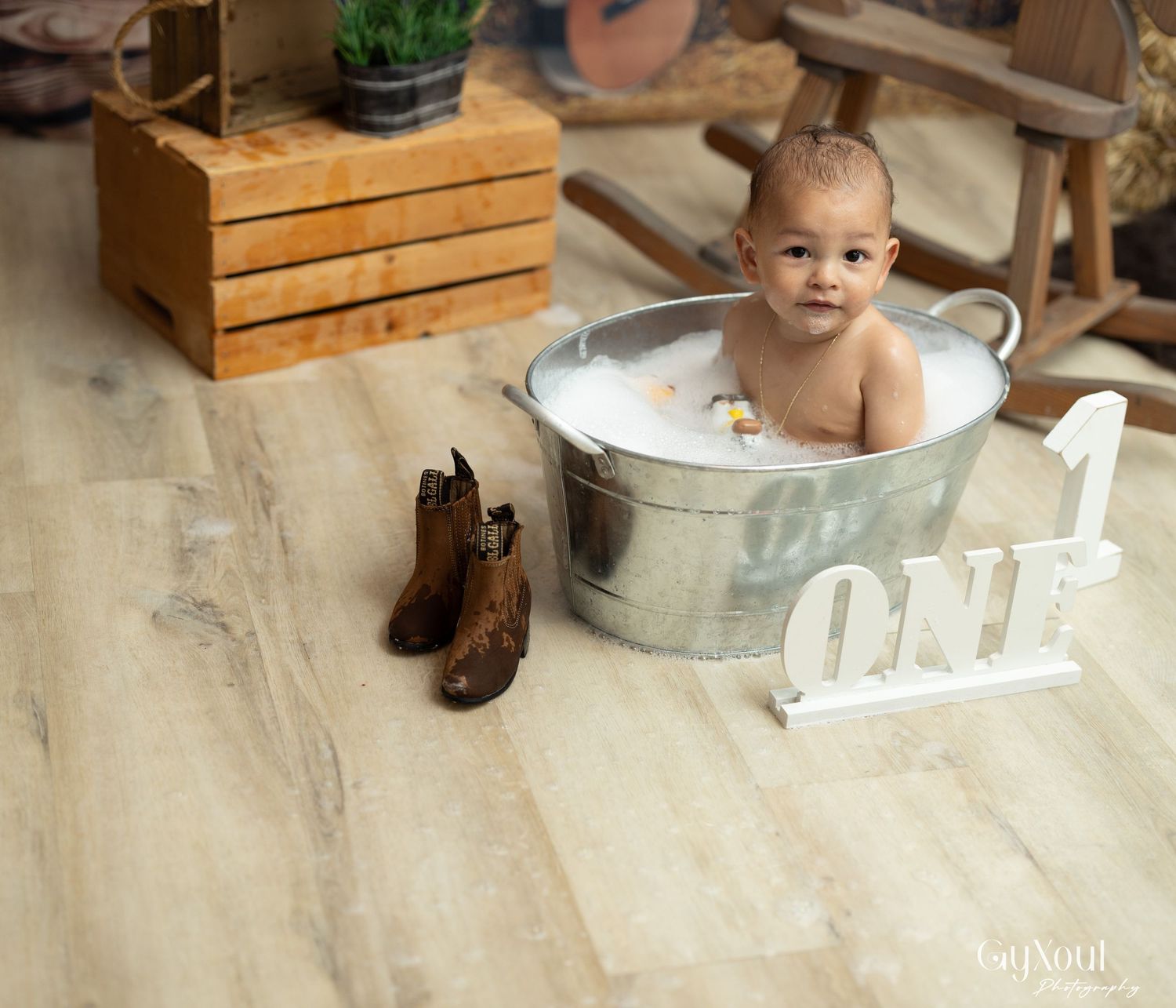 A baby enjoys a rustic wooden first birthday photo shoot with milk crates and numbered decor.