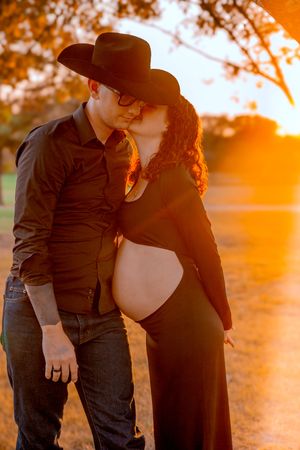 Romantic maternity photos taken during golden hour showing tender moments in a field.