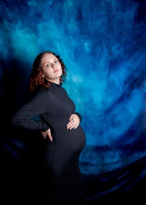 Artistic maternity portraits against blue backdrop showing elegant poses in black attire.