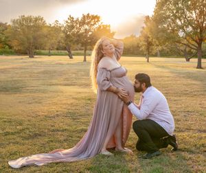 A maternity photo session in a field at sunset with flowing fabric creating an ethereal effect.